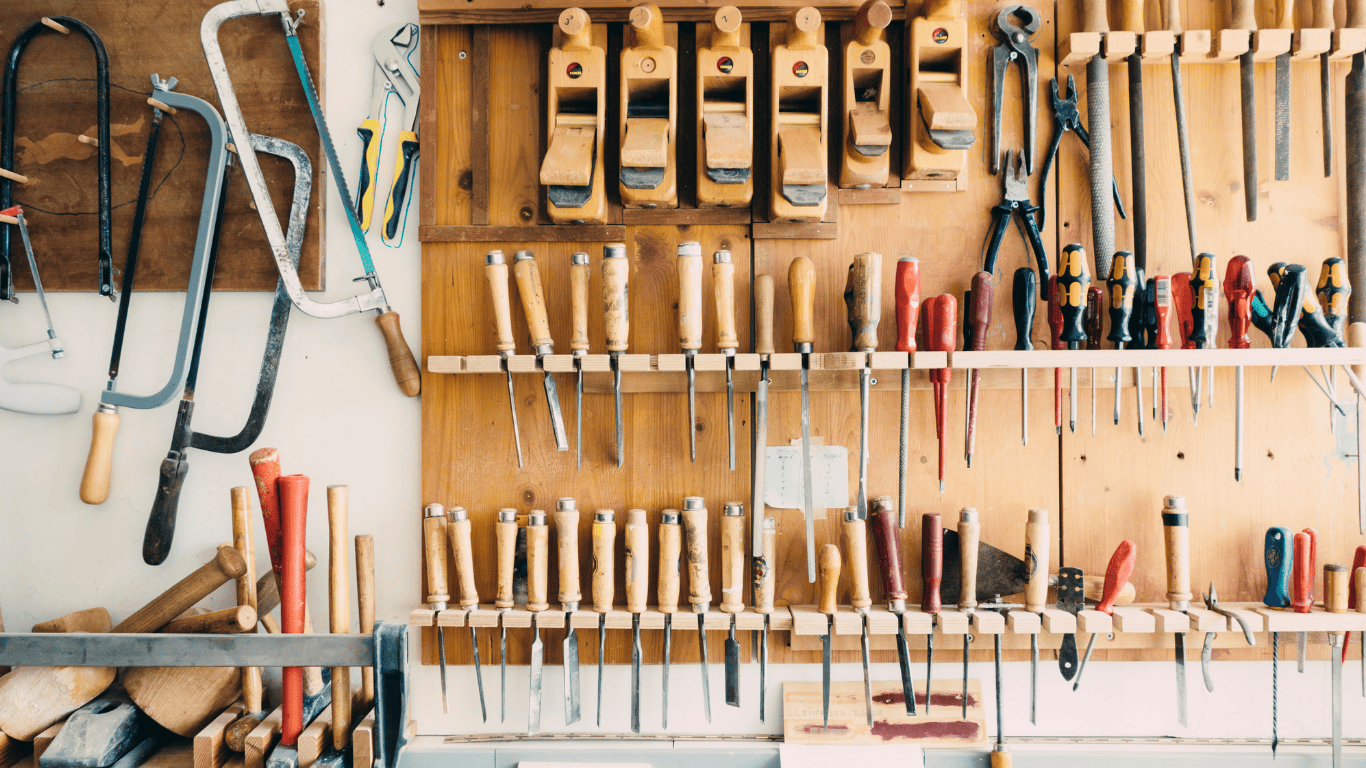 Various hand tools neatly organized and hanging on a workshop wall.