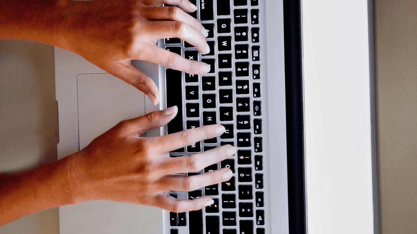 Close-up of hands typing on a laptop keyboard.