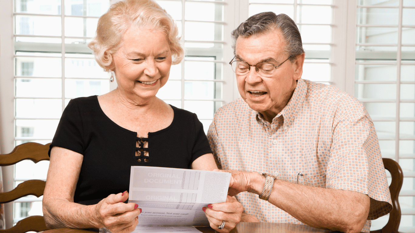 Smiling senior couple sitting at a table reviewing documents together.