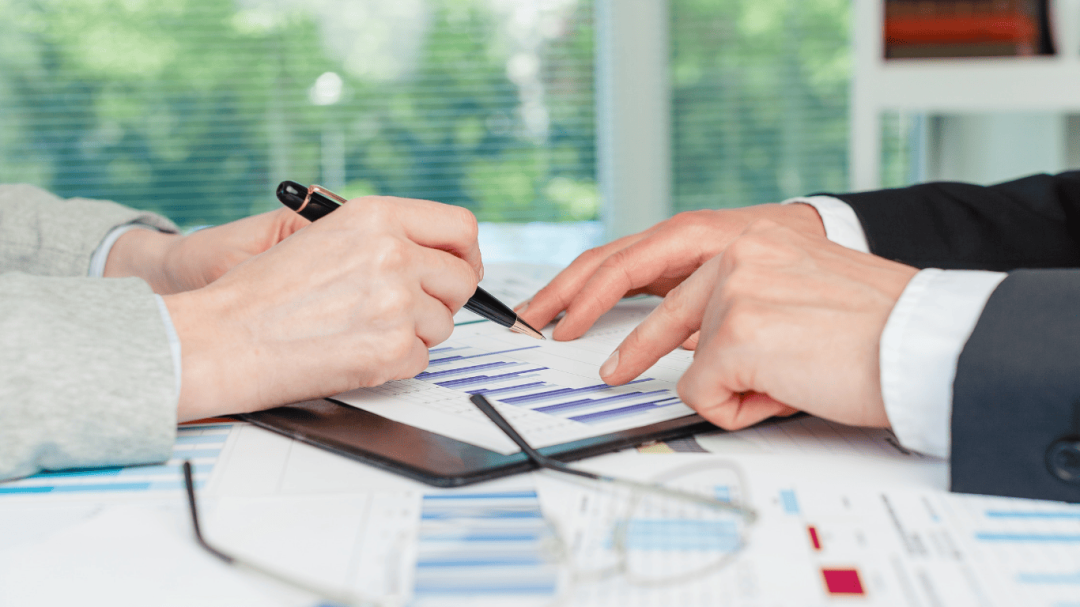 Close-up of two professionals discussing financial charts and graphs during a business meeting.