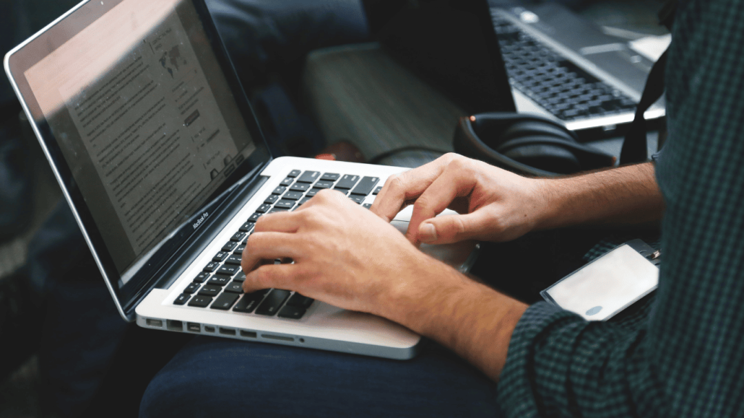 Close-up of a person typing on a laptop while working.