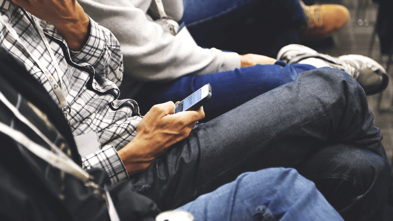 Person sitting and using a smartphone during a conference or meeting.