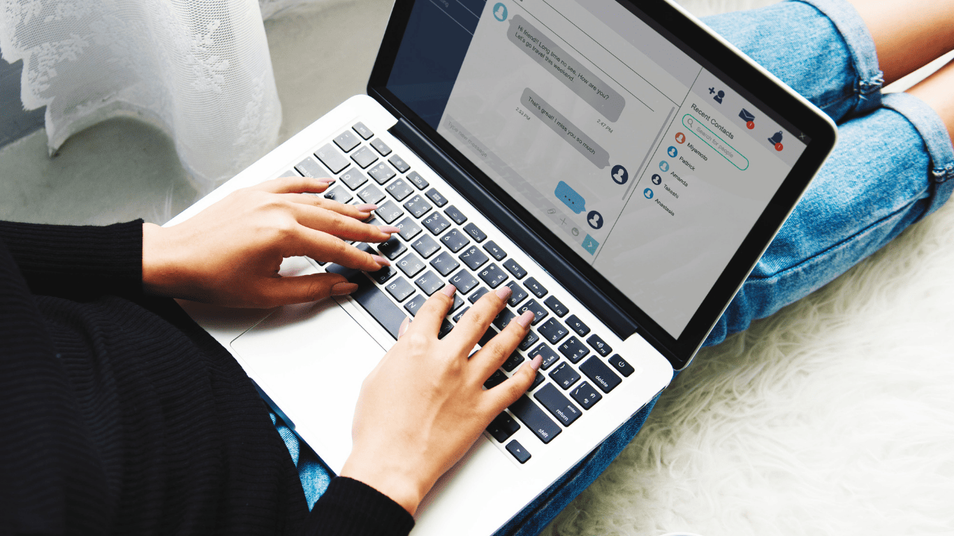 Woman typing on a laptop while chatting through an online messaging app.