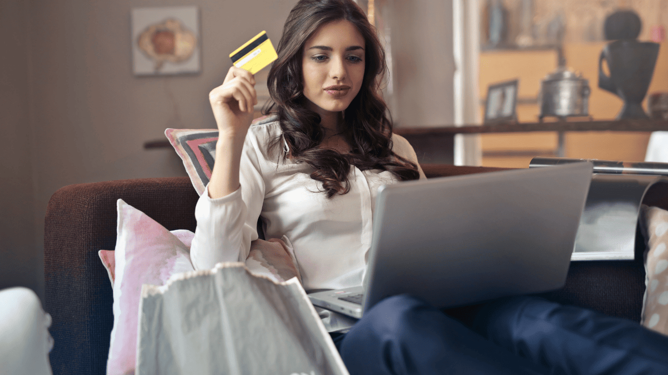 Woman holding a credit card while shopping online using a laptop.