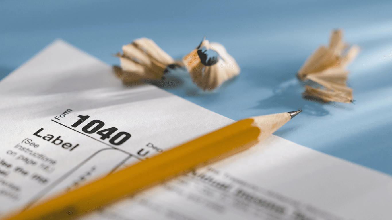 Close-up of a sharpened pencil on IRS Form 1040 with pencil shavings on a desk.