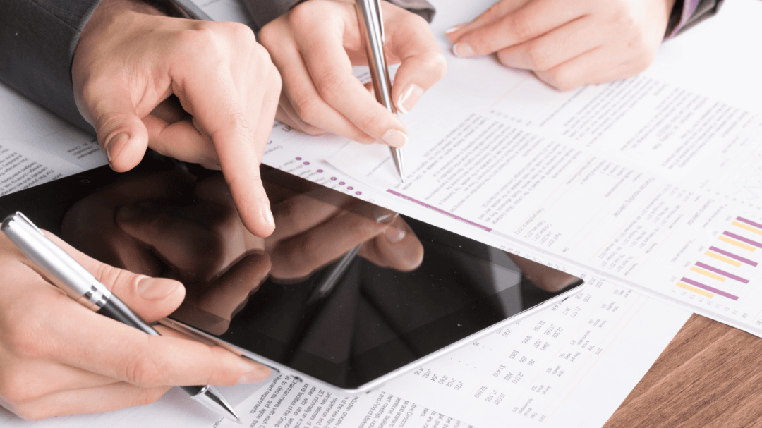 Team reviewing financial reports and analyzing data using a tablet and documents.