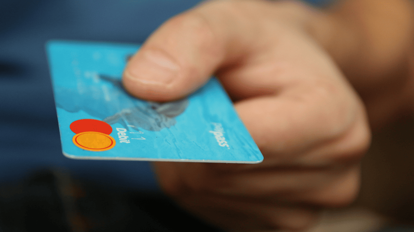 Close-up of a hand holding a blue debit card.