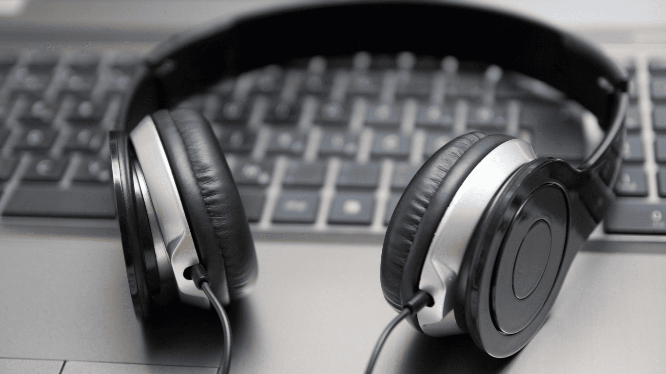 Black headphones placed on a laptop keyboard.