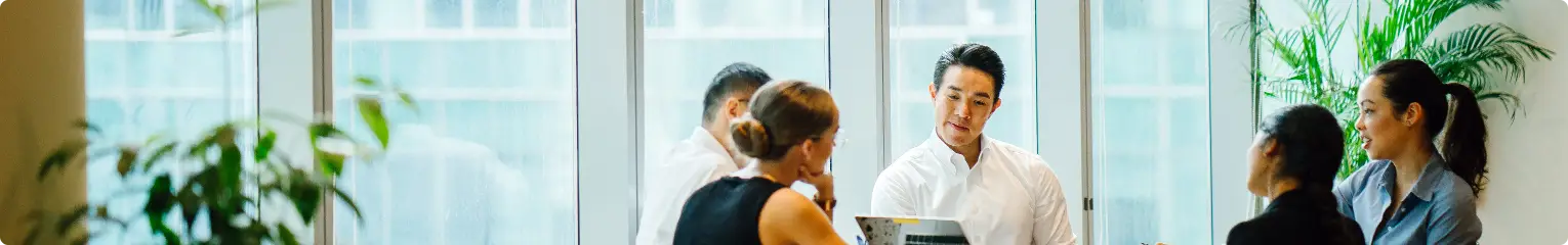 Office colleagues discussing work while seated around a table.